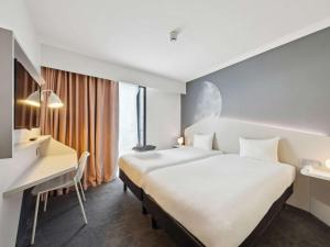 ein Hotelzimmer mit 2 Betten und einem Schreibtisch in der Unterkunft ibis Styles Paris Charles de Gaulle Airport in Roissy-en-France