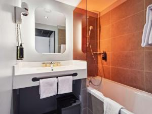 ein Badezimmer mit einem Waschbecken, einer Badewanne und einem Spiegel in der Unterkunft ibis Styles Paris Charles de Gaulle Airport in Roissy-en-France
