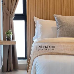 Una cama con una almohada que dice que la suite layonite del kit de costa en The Shore CBD Kota Kinabalu By LAXZONE SUITE en Kota Kinabalu
