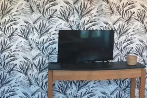 a television sitting on a table in front of a wallpaper at Bienvenue chez nous 