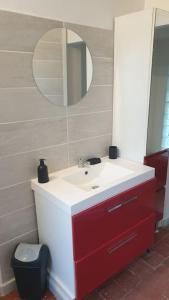 a bathroom with a red and white sink and a mirror at Bienvenue chez nous 