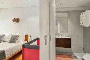 a bedroom with a bed and a bathroom with a sink at Host Wise - Lovely Shinny Flats with Balcony - Clerigos in Porto +63 photos