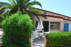 una palmera frente a una casa con una mesa en Lagrange Grand Bleu Vacances – Résidence Les Jardins de Neptune, en Saint-Cyprien