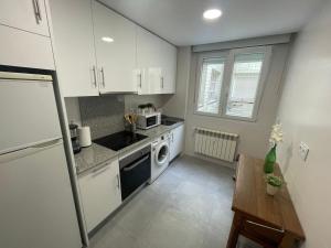uma pequena cozinha com armários brancos e um micro-ondas em Piso cerca de las estaciones em Santander