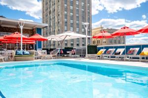 a swimming pool with umbrellas and tables and chairs at Unscripted Durham, Part of JDV by Hyatt in Durham
