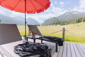 a patio with a table and a red umbrella at Loisi's Boutiquehotel in Achenkirch