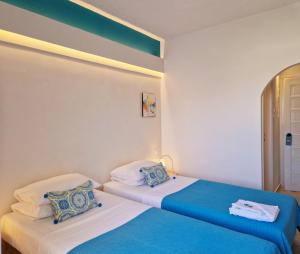 two beds in a room with blue and white at Boutique Hotel Die Zwei Brüder in Matala