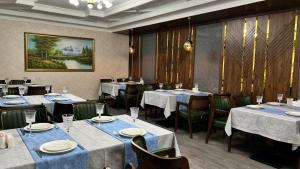 a dining room with tables and chairs with blue linens at Za'faron Hotel in Jizzax