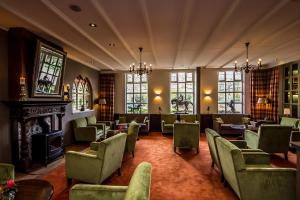 a waiting room with chairs and a fireplace and windows at Landhuishotel De Bloemenbeek in De Lutte