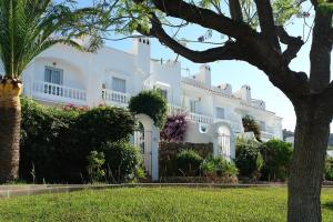 a large white house with trees and bushes at JARDINES DE NERJA 18 MENYBER in Nerja