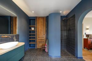 La salle de bains est pourvue de murs bleus, d'une baignoire et d'un lavabo. dans l'établissement La Paulowna Boutique Hotel, à La Haye