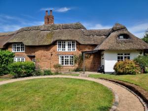 an old stone house with a thatched roof at Castle Hill Cottage on a Scheduled Monument in Kenilworth