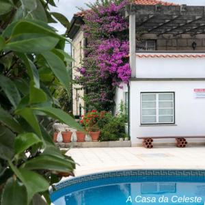 una casa con fiori viola accanto a una piscina di A Casa da Celeste a Fagilde