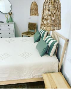 Schlafzimmer mit einem Bett mit grünen und weißen Kissen in der Unterkunft Quinta Almargem Lusitano - Farm House in Tavira