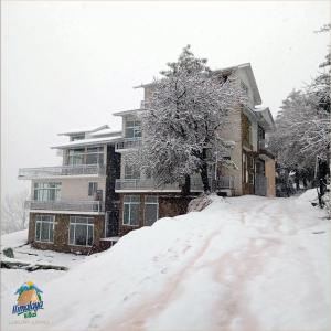 a snow covered house in front of a house at Himalaya Villas in Murree