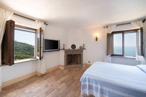 - une chambre blanche avec une cheminée et une télévision dans l'établissement Torre del Saraceno, à Massa Lubrense