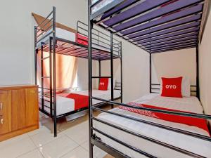 1 dormitorio con 2 literas con almohadas rojas en OYO 92617 Omahku Homestay Hostel, en Yogyakarta