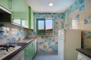 a kitchen with green and blue tiled walls and a refrigerator at O búzio in Albufeira