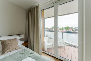 a bedroom with a bed and a balcony with a view of the water at Penthouse Lighthouse Mrzeżyno SurfingBird in Mrzeżyno