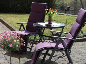 dos sillas moradas y una mesa con un jarrón de flores en Apartment in the centre of the Eifel, en Strotzbüsch