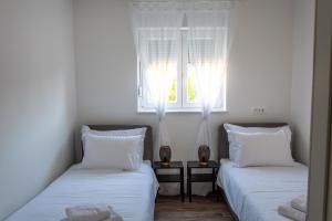 dwa łóżka w pokoju z oknem w obiekcie Apartman Sistov w mieście Kaštela