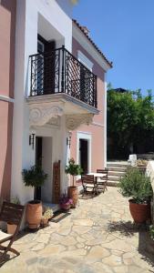 a building with a balcony and tables and potted plants at Αρχοντικό Ταξίμι (Μουντζουρίδη) in Argalasti