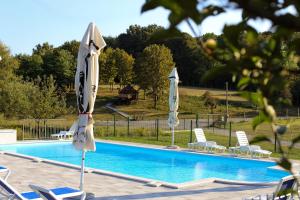 a swimming pool with chairs and umbrellas next to it at GLAMPING IZLETIŠTE BANOVAC in Gornje Komarevo