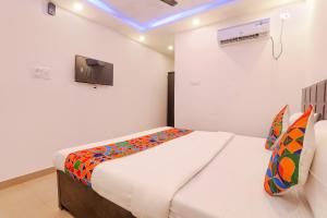 1 dormitorio con 1 cama y TV en la pared en FabExpress Elite Inn, en Patna
