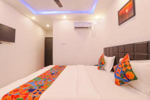 a bedroom with a large white bed with colorful pillows at FabExpress Elite Inn in Patna