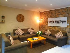 una sala de estar con 2 sofás y un reloj en la pared en Gooderson Leisure Mountain View Cottages Self Catering and Timeshare Resort, en Drakensberg Garden