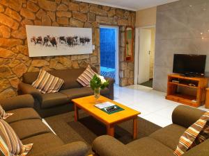 uma sala de estar com sofás e uma parede de pedra em Gooderson Leisure Mountain View Cottages Self Catering and Timeshare Resort em Drakensberg Garden
