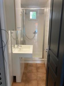 La salle de bains blanche est pourvue d'un lavabo et d'une douche. dans l'établissement L’appartement du Micocoulier, à Salon-de-Provence