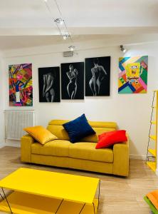 sala de estar con sofá amarillo y cuadros en la pared en POP appART Appartement Artiste 200 m du centre ville Parking privé gratuit, en Aviñón