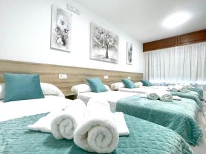 a room with four beds with towels on them at Pension O Camiño Milladoiro in Amés