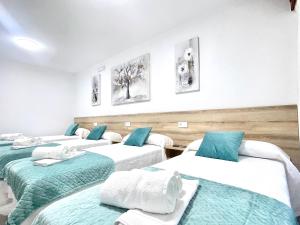 three beds in a room with blue and white at Pension O Camiño Milladoiro in Amés
