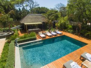 una piscina infinita con sillas y cenador en Garden Retreat Guest House, en Ciudad del Cabo