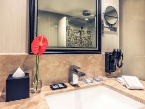 a bathroom with a sink with a red flower on it at Mercure Bangkok Sukhumvit 11 in Bangkok