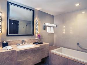 a bathroom with a sink and a tub and a mirror at Mercure Bangkok Sukhumvit 11 in Bangkok