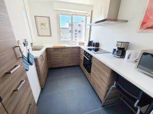 a small kitchen with wooden cabinets and a window at Appartement Cosy et Lumineux - Tout équipé - Hypercentre Lorient par Groom in Lorient