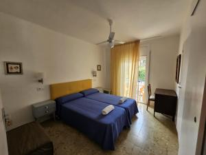 a bedroom with a blue bed and a chair at Hostal Cruz in Tossa de Mar