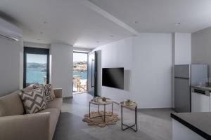 ein Wohnzimmer mit einem Sofa, einem TV und einem Tisch in der Unterkunft Sea Front Salty Sea Suites Estate in Agios Nikolaos