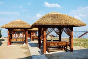 een groep banken met rieten parasols op het strand bij Waterloo Village in Pidhorodne