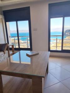 a living room with a table with a view of the ocean at Appartement Sable blanc in Al Hoceïma