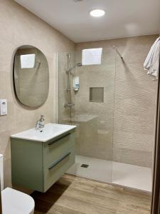 a bathroom with a shower and a sink and a mirror at Apartamento Valbuena in Potes