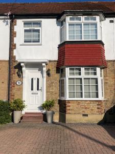 a white house with a red roof at Modern 4-bedroom entire house with Garden in Uxbridge