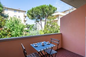 a table and chairs on a balcony with a view of a building at Homiday - New House - Pisa Aeroporto - Free Parking in Pisa