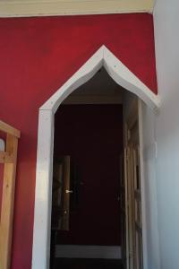 an opening to a hallway with a red wall at The Pink House in Faja Grande