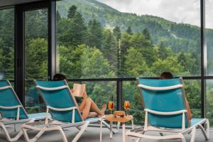 Dos mujeres sentadas en sillas en un balcón con vistas a las montañas en Hotel Nomad, en Bjelašnica