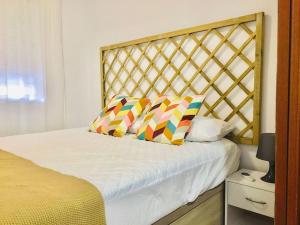 Una cama con dos almohadas de colores encima. en Apartamento ABRIL en el Centro de Getafe, en Getafe