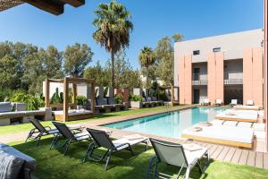 a swimming pool with lounge chairs and a hotel at Pilot Amphora Boutique Hotel "Adults Only" in Georgioupolis